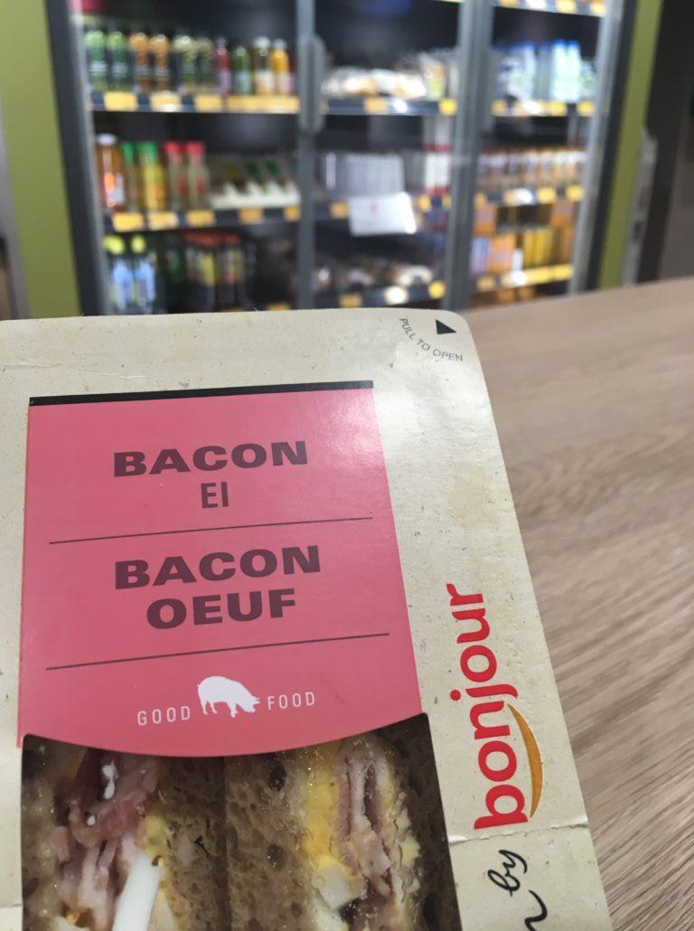 Broodje bacon ei met schappen op de achtergrond bij benzinestation