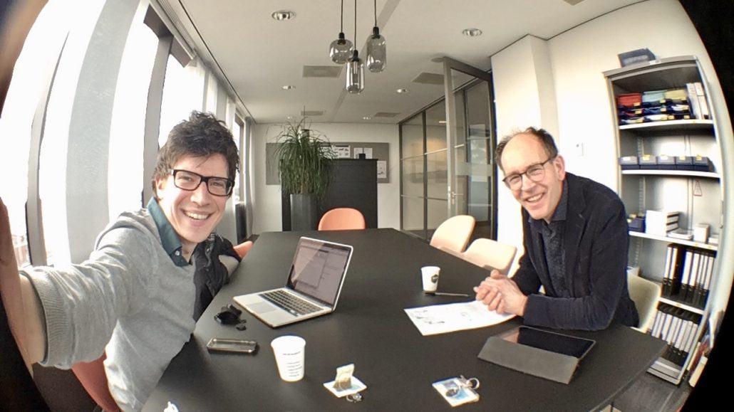 twee mannen die lachen aan tafel kijken in camera